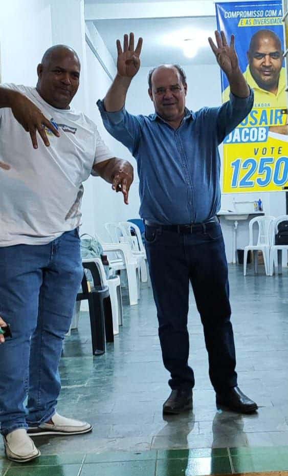 Mosair trajando camisa branca e fazendo a letra M com as mãos. Edmário trajando azul fazendo o 44 com as duas mãos